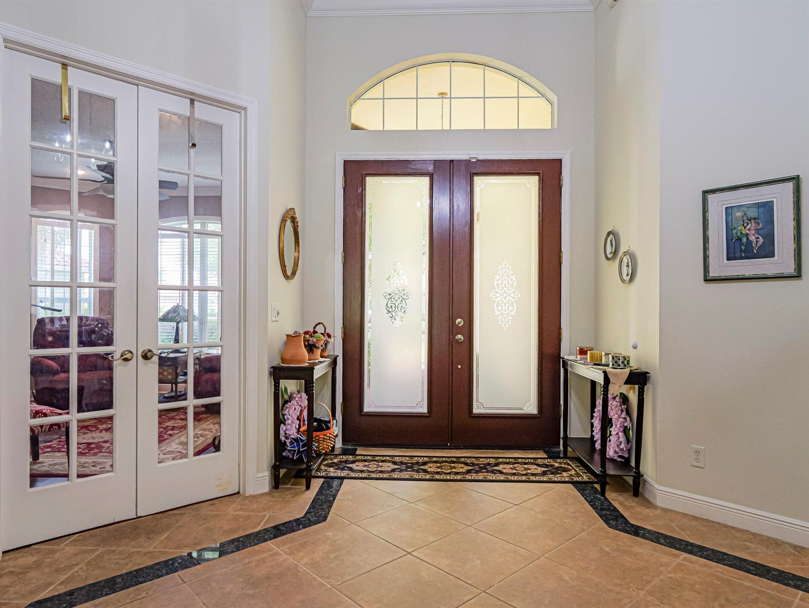 An entryway features double front doors with glass inserts, tile flooring, and two side tables — 5873 Pine Ridge Circle, Vero Beach FL 32967, VERO BEACH, FL