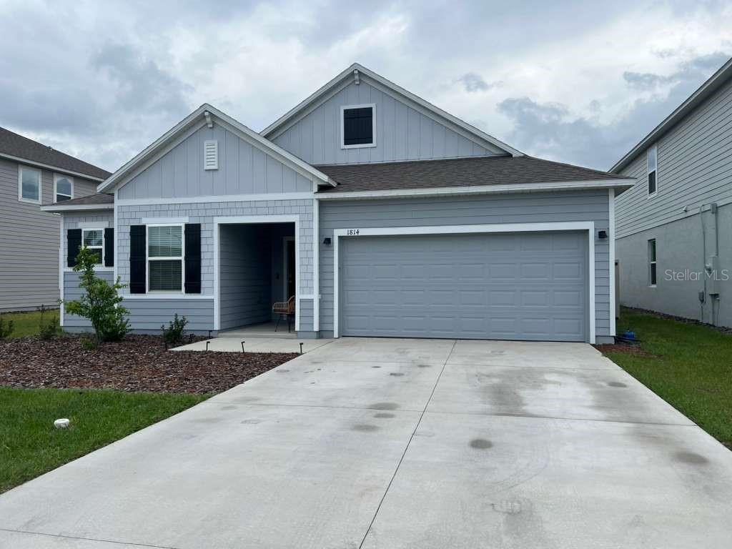 A light blue single-story house with a two-car garage and a concrete driveway — 1814 NW 248TH WAY, NEWBERRY, FL