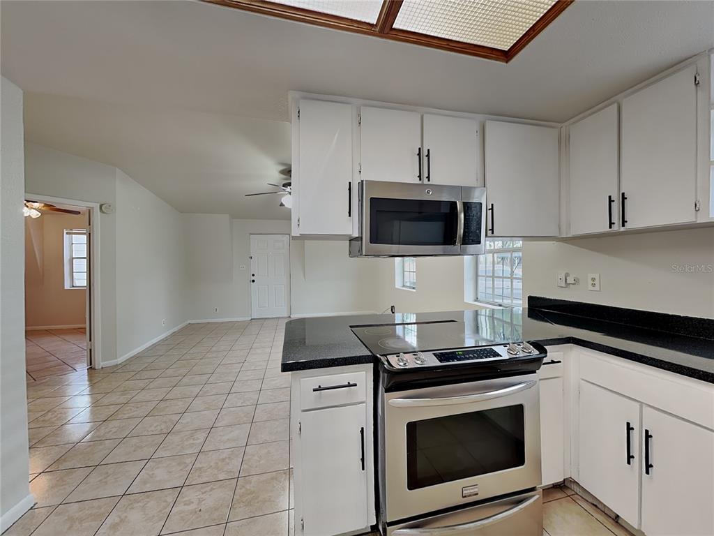 A room with a slanted wall, tile flooring, a ceiling fan, and double glass doors — 9213 N 13TH STREET, TAMPA, FL