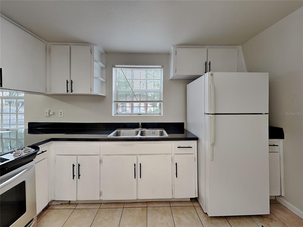 An empty room with beige tile flooring, white walls, a ceiling fan, and two windows — 9213 N 13TH STREET, TAMPA, FL