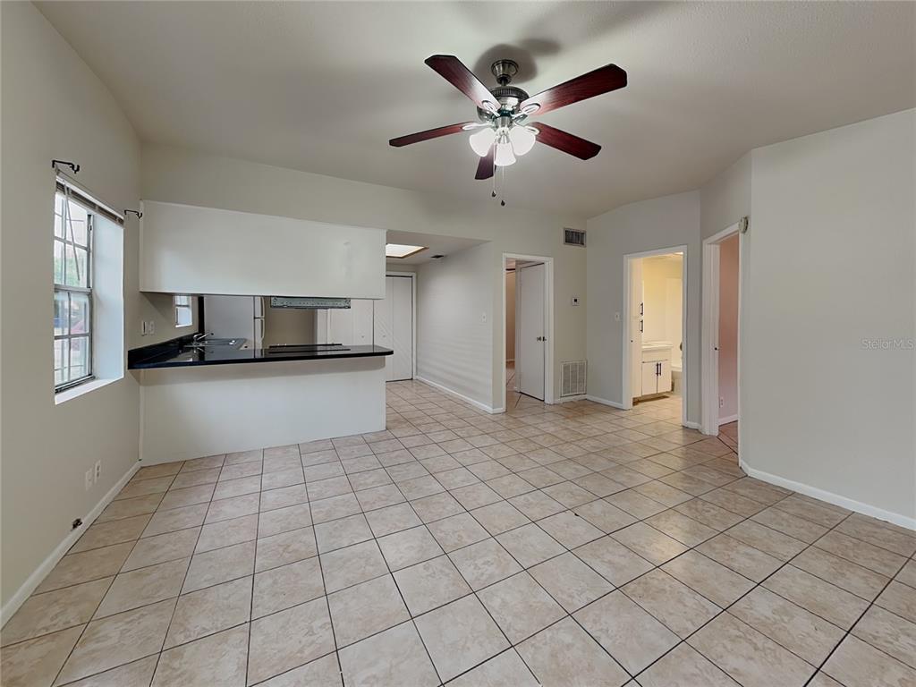 A living room with light-colored tile floors, two windows, and an open kitchen area — 9213 N 13TH STREET, TAMPA, FL