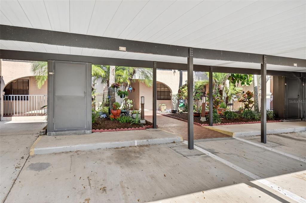 A covered carport area leads to a landscaped walkway and building entrance — 23465 HARBORVIEW ROAD UNIT 814, PUNTA GORDA, FL