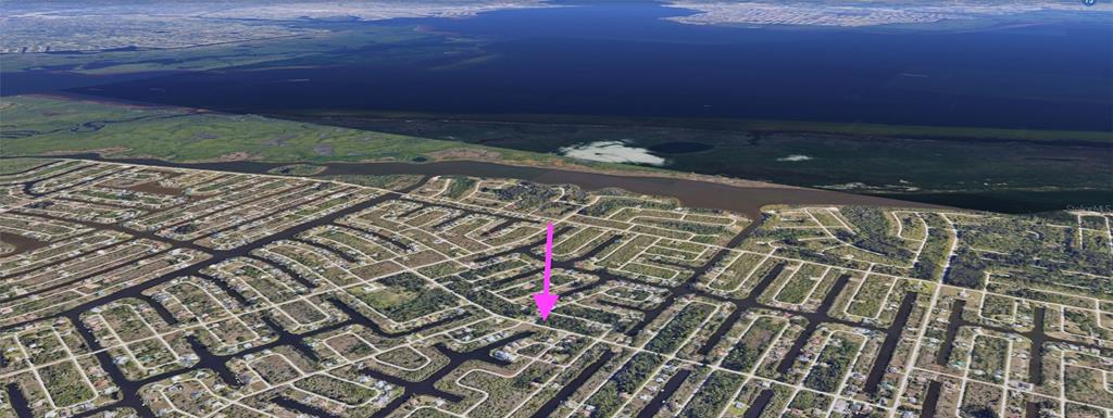 An aerial view of a residential neighborhood with canal-front homes and a pink arrow pointing down — 15249 RED HEAD AVENUE, PORT CHARLOTTE, FL