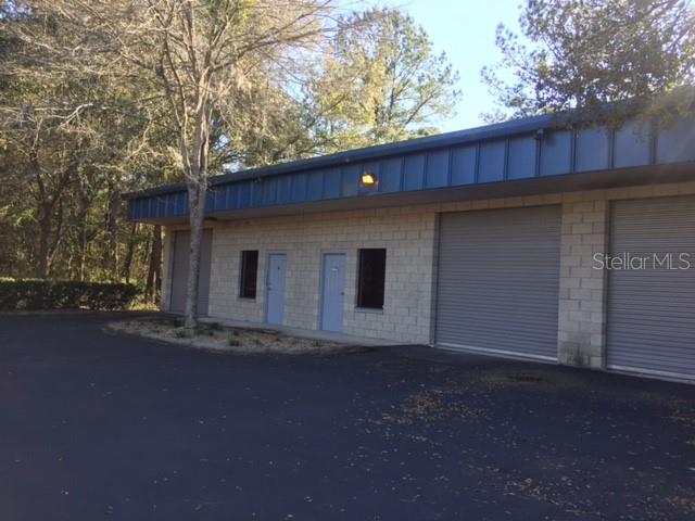 A single-story commercial building with light-colored block walls, two roll-up doors, and two entry doors — 4577 NW 6TH STREET UNIT A/B, GAINESVILLE, FL