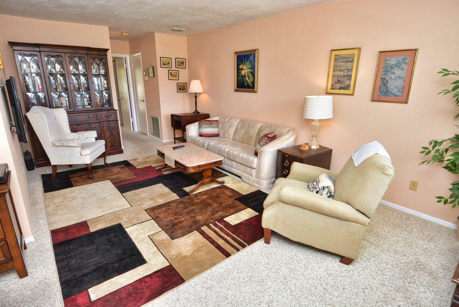 A living room features a patterned area rug, a sofa, two armchairs, and a hutch — 1225 NW 21st Street # 2010, Stuart FL 34994, STUART, FL