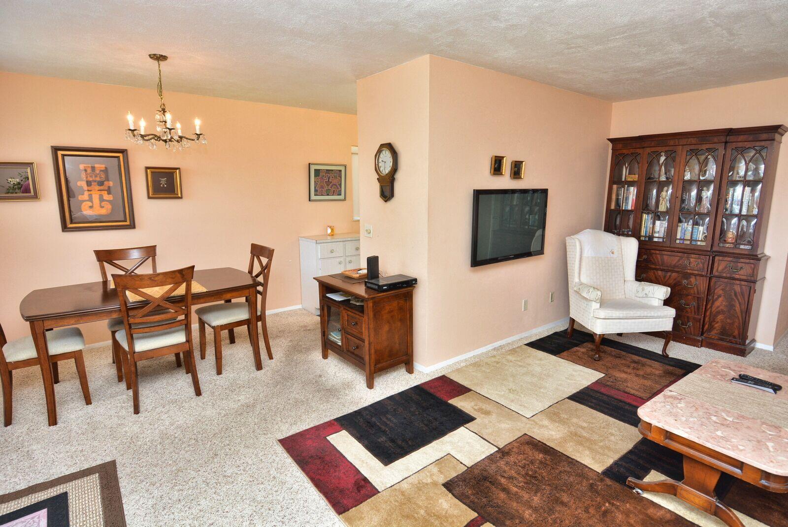 A dining area and living room feature beige walls, carpeted floors, and a wooden hutch — 1225 NW 21st Street # 2010, Stuart FL 34994, STUART, FL