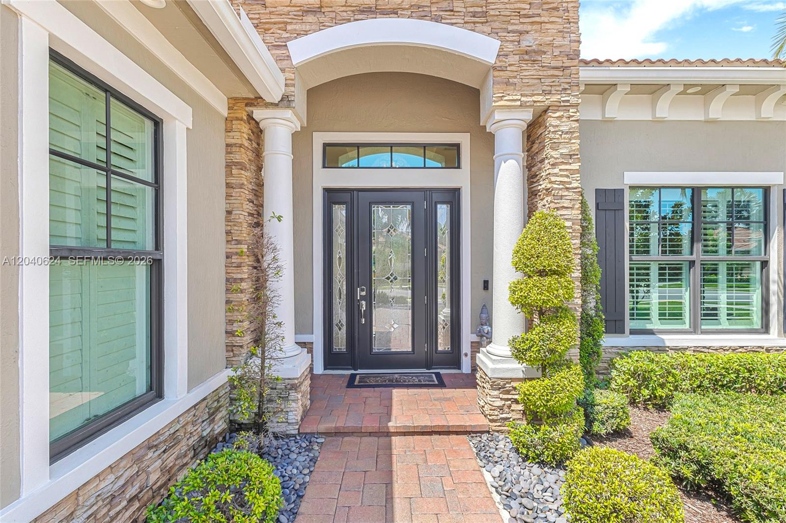 The front entrance features a dark glass door flanked by columns and stone veneer siding — 11930 Palermo Rd, Parkland FL 33076, PARKLAND, FL