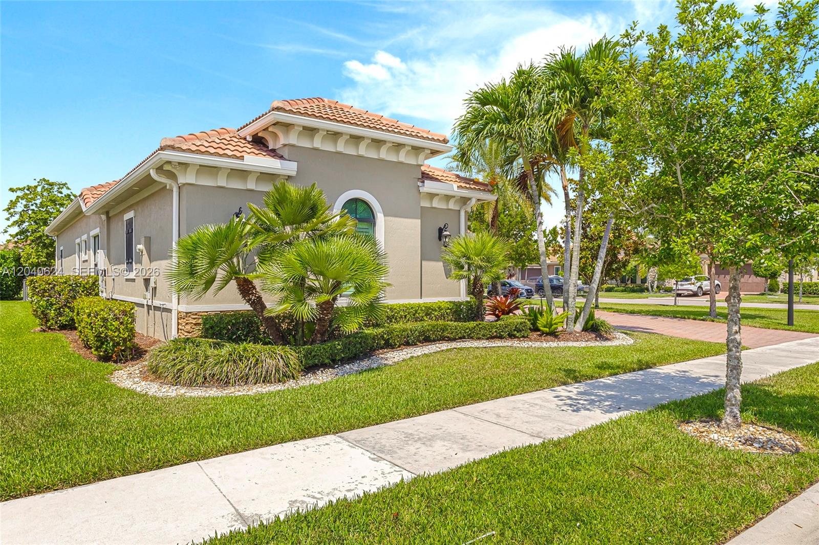A tan, single-story house with a tile roof and palm trees sits beside a sidewalk — 11930 Palermo Rd, Parkland FL 33076, PARKLAND, FL