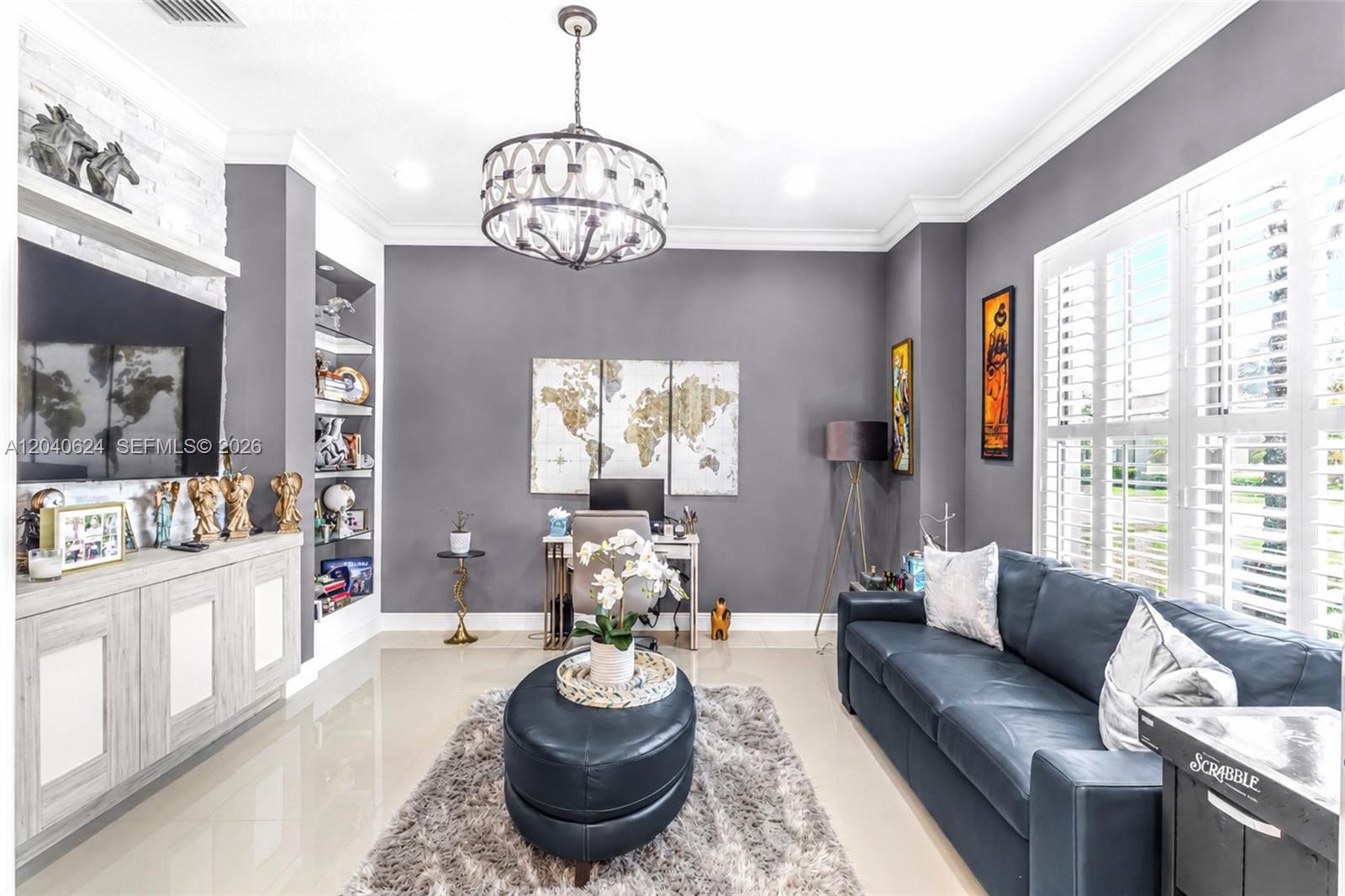 A living room features a dark leather sofa, a central ottoman, and a home office area — 11930 Palermo Rd, Parkland FL 33076, PARKLAND, FL