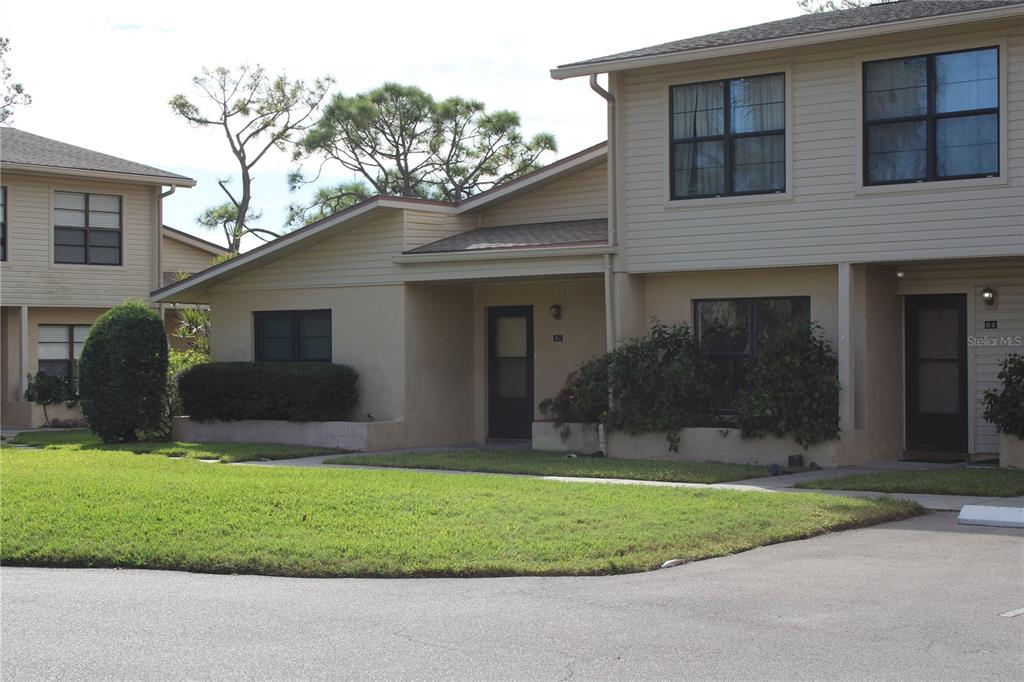 A two-story tan townhouse exterior features a front lawn, paved driveway, and dark-framed windows — 3602 54TH STREET W UNIT D1, BRADENTON, FL