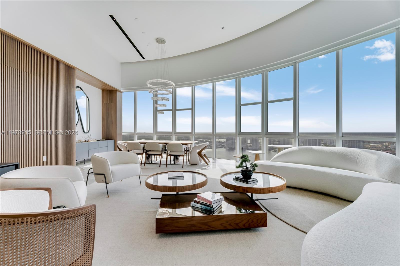 A modern living and dining area features floor-to-ceiling windows with panoramic water and city views — 18201 E Collins Ave, Sunny Isles Beach FL 33160, SUNNY ISLES BEACH, FL