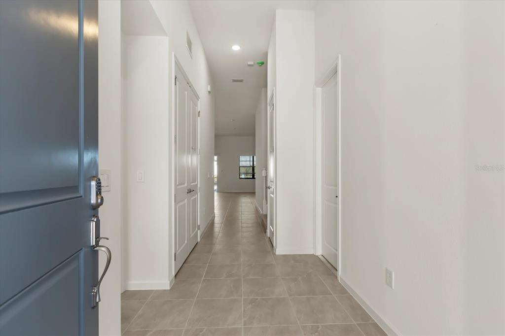 A view from an open doorway looking down a tiled hallway toward a distant window — 11073 MORAY BAY AVE, ORLANDO, FL