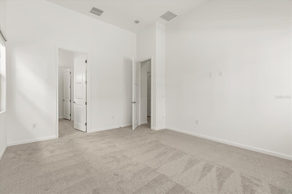An empty bedroom with white walls, gray carpet, and two open doorways — 11073 MORAY BAY AVE, ORLANDO, FL