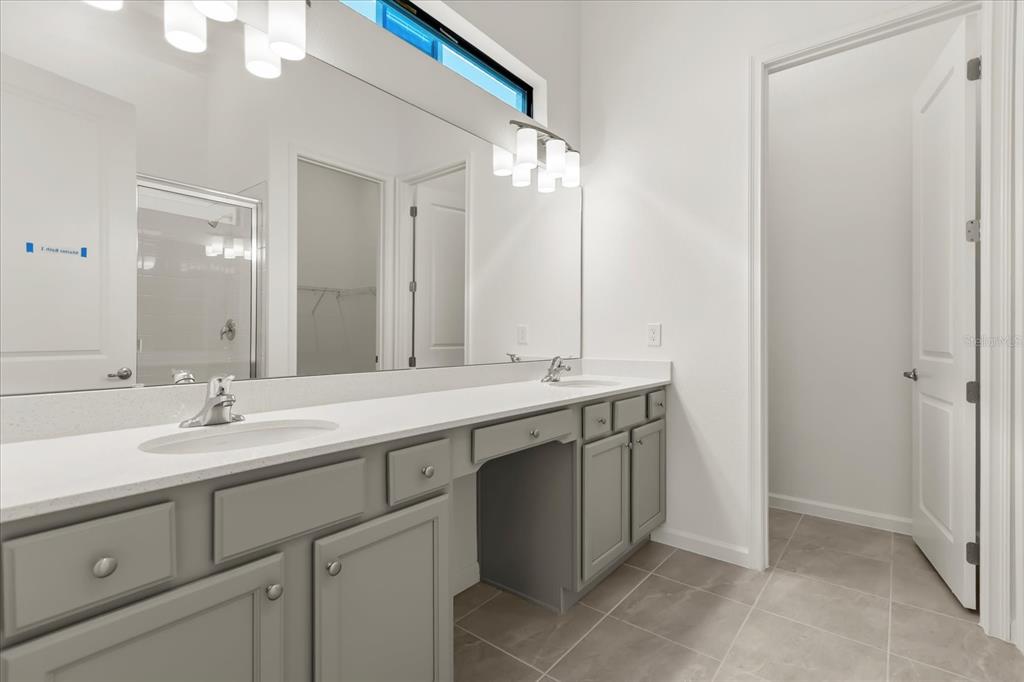 A bathroom features a double vanity with gray cabinets, white countertops, and a large mirror — 11073 MORAY BAY AVE, ORLANDO, FL
