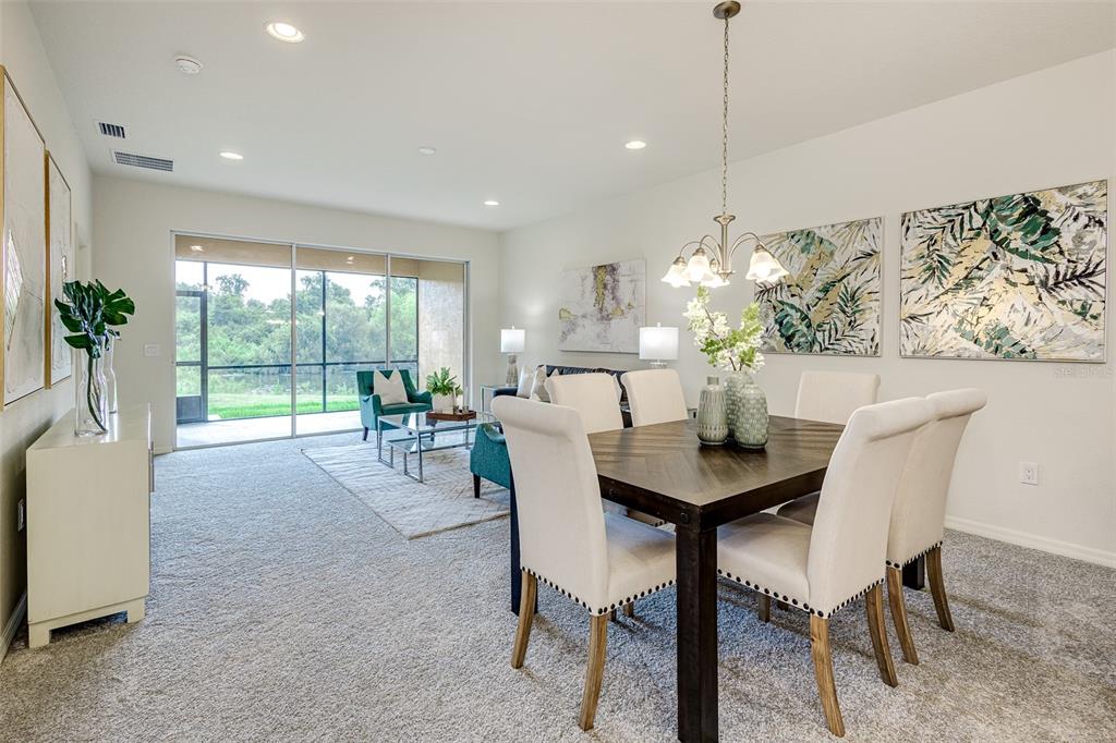 A dining area with a dark wood table and chairs opens to a carpeted living room — 1703 LINZ COURT, WINTER HAVEN, FL