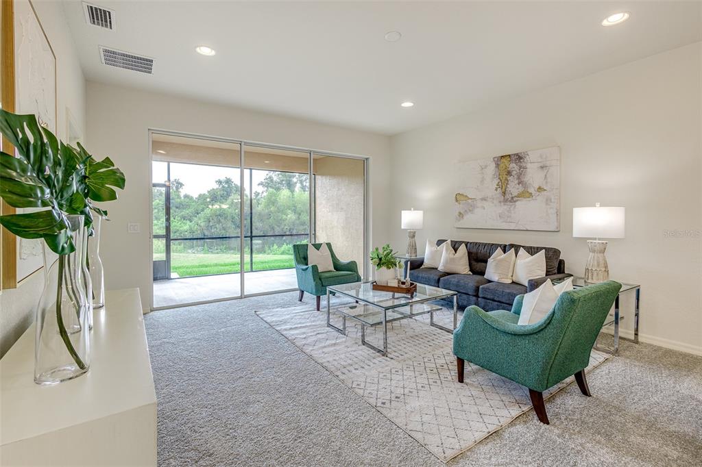 A living room features a dark sofa, two teal armchairs, and sliding glass doors — 1703 LINZ COURT, WINTER HAVEN, FL