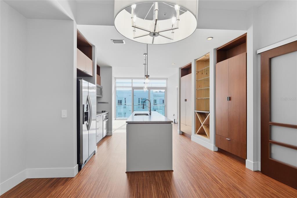 A modern kitchen features a central island, wood flooring, and floor-to-ceiling cabinetry — 111 N 12TH STREET UNIT 1811, TAMPA, FL