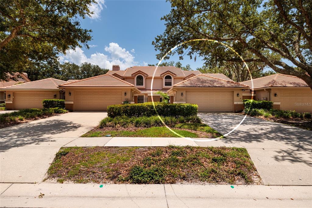 A view of the exterior of a tan, multi-unit residential building with tile roofs — 17557 FAIRMEADOW DRIVE, TAMPA, FL