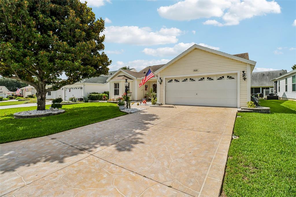 A tan house exterior features a stone walkway, white gravel landscaping, and potted flowers — 16581 SE 77TH NORTHRIDGE COURT, THE VILLAGES, FL