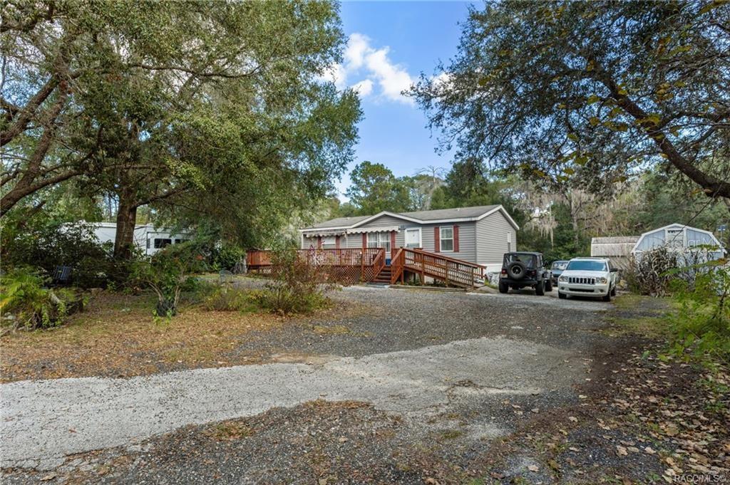 A single-story house with a wooden deck and ramp sits on a gravel driveway — 16362 CHEROKEE ROAD, BROOKSVILLE, FL