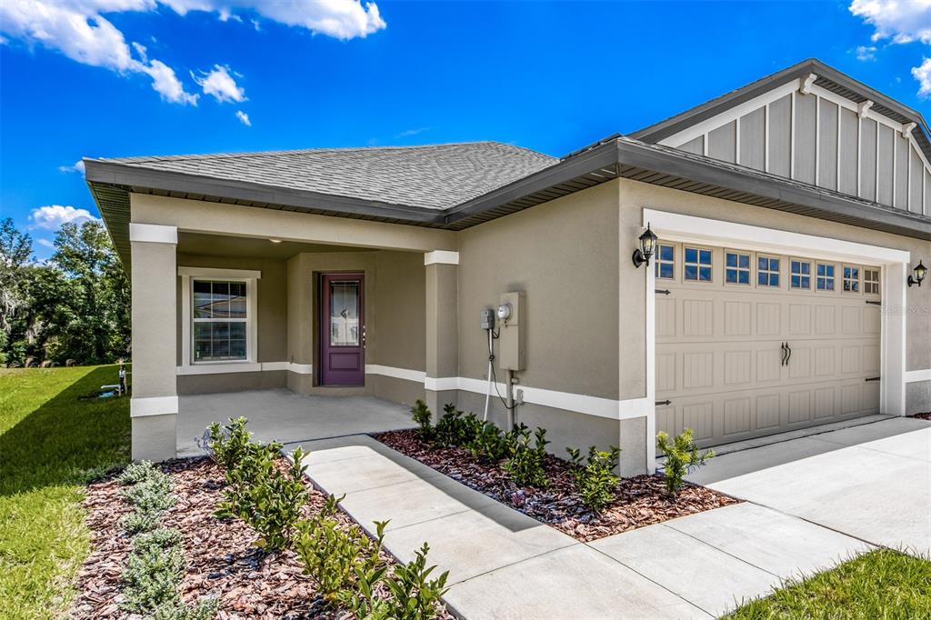A tan single-story house exterior with a purple front door and a two-car garage — 3187 SEVILLE STREET, LAKE ALFRED, FL