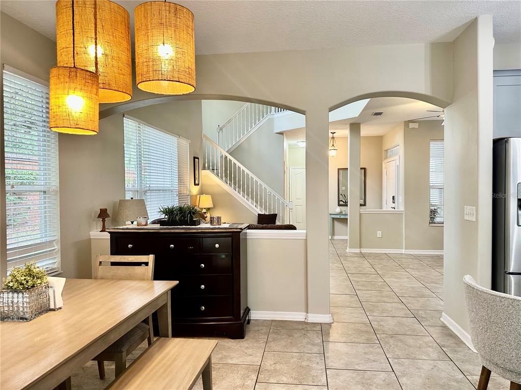 A dining area with pendant lights leads to an arched opening revealing a staircase — 12014 DEACONS CROFT LANE, TAMPA, FL
