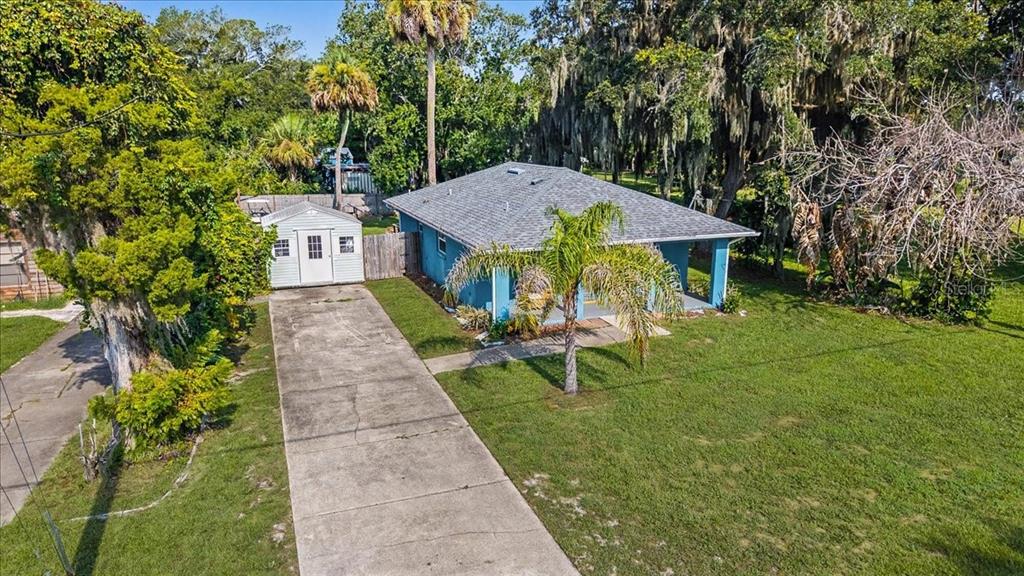 An aerial view shows a blue house with a gray roof and a concrete driveway — 156 GAINES STREET, OAK HILL, FL