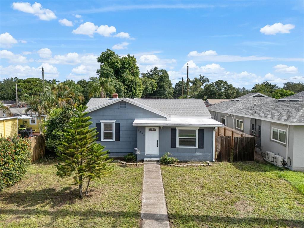 A single-story gray house with a white door and a concrete walkway in the yard — 5345 38TH AVENUE N, ST PETERSBURG, FL