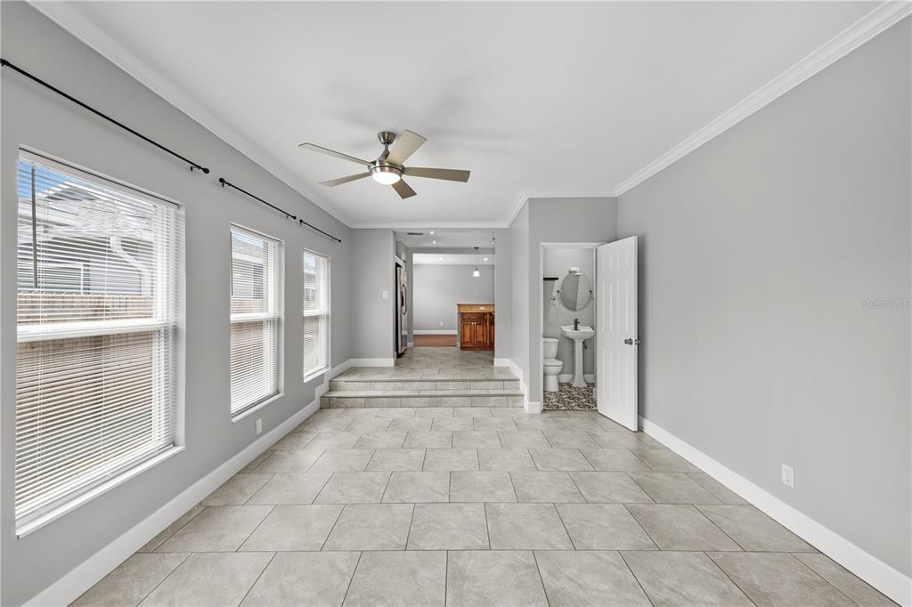 A room with gray tile flooring, a ceiling fan, and a step up to another area — 5345 38TH AVENUE N, ST PETERSBURG, FL