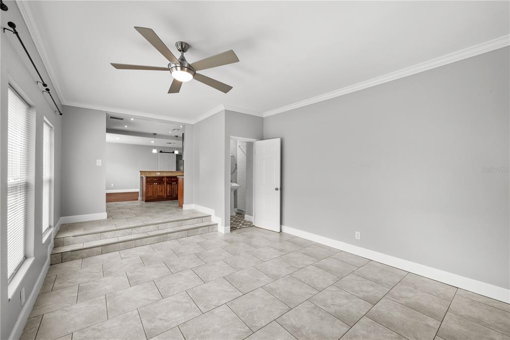 A room with gray walls, tile flooring, a ceiling fan, and a step-up kitchen area — 5345 38TH AVENUE N, ST PETERSBURG, FL