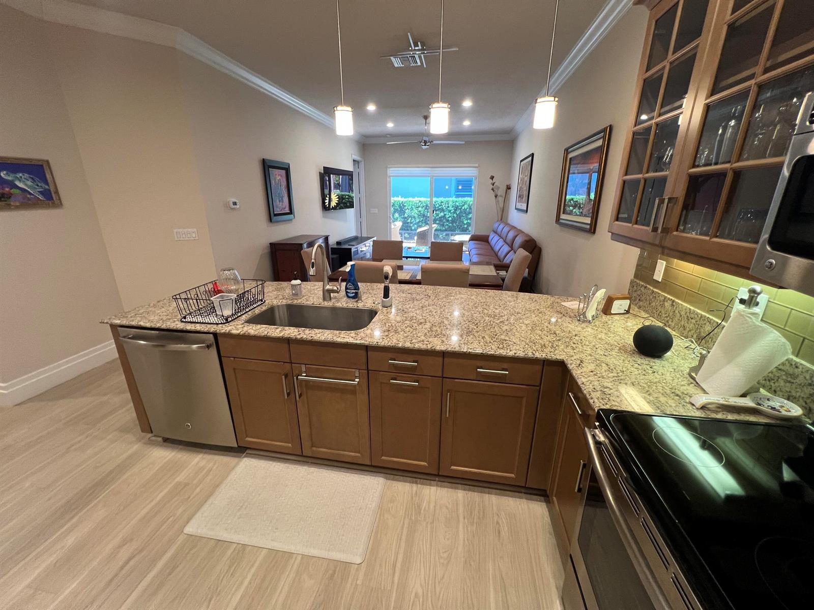 A kitchen with granite countertops and stainless steel appliances overlooks a dining and living area — 14856 Barletta Way, Delray Beach FL 33446, DELRAY BEACH, FL