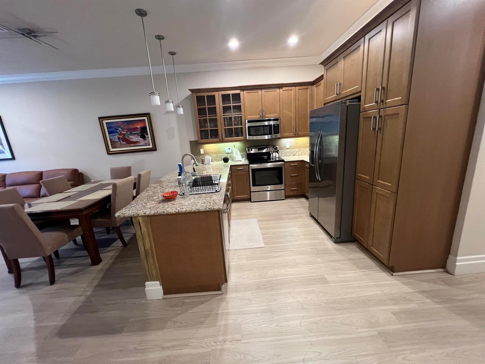 A kitchen features wood cabinets, granite countertops, stainless steel appliances, and an adjacent dining area — 14856 Barletta Way, Delray Beach FL 33446, DELRAY BEACH, FL