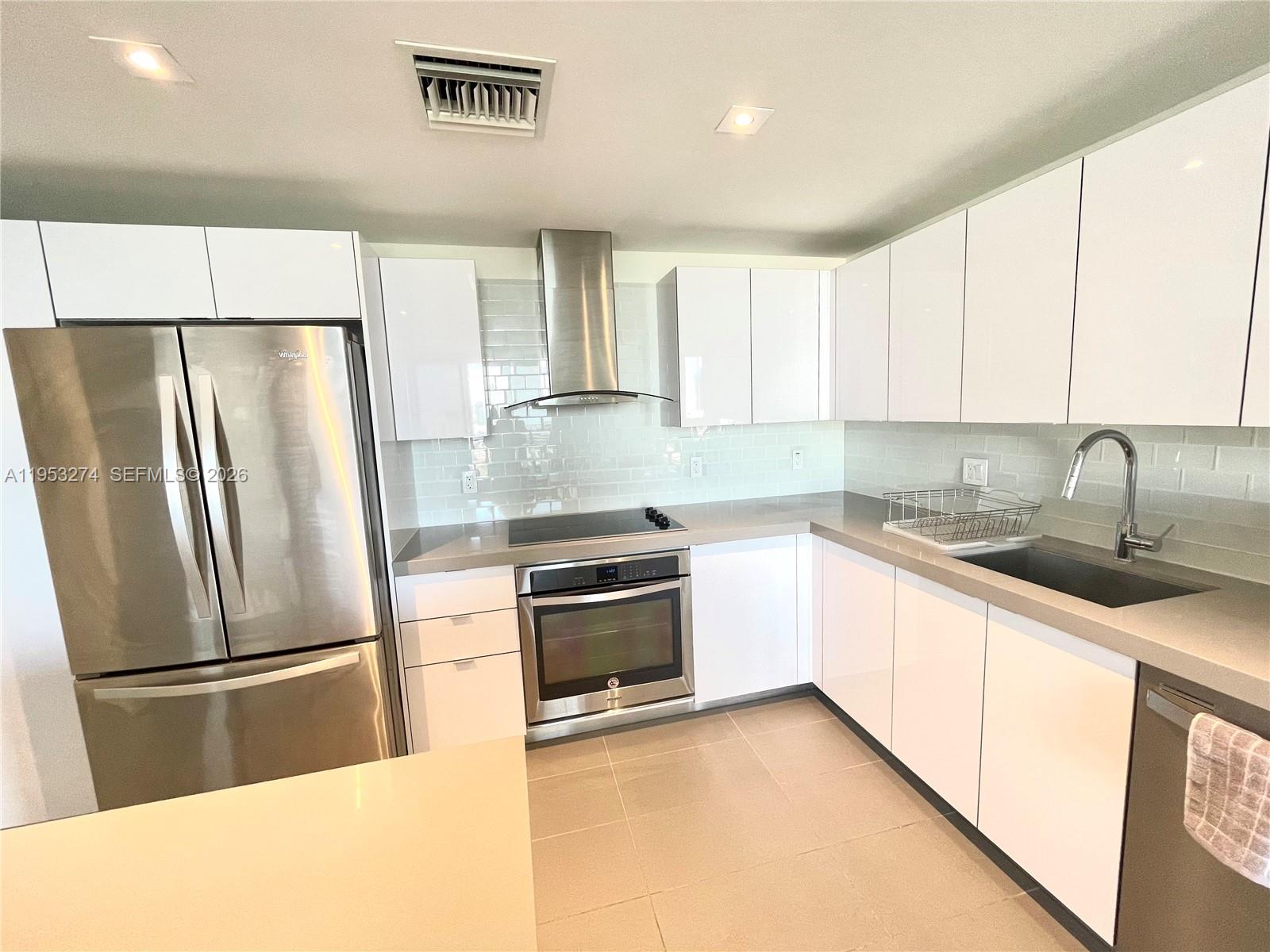 A modern kitchen features white cabinets, stainless steel appliances, and light-colored countertops — 1600 NE 1st Ave # 1018, Miami FL 33132, MIAMI, FL