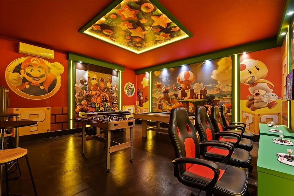 A Super Mario-themed game room featuring a foosball table, pool table, and several gaming chairs — 3083 MAHALO DRIVE, DAVENPORT, FL