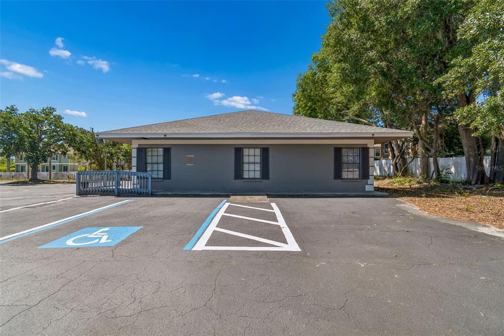 A gray, single-story commercial building features a wheelchair ramp and a designated handicap parking space — 7511 LITTLE ROAD, NEW PORT RICHEY, FL