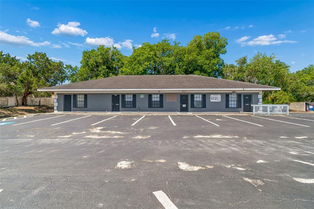 A single-story gray commercial building with a parking lot in the foreground — 7511 LITTLE ROAD, NEW PORT RICHEY, FL