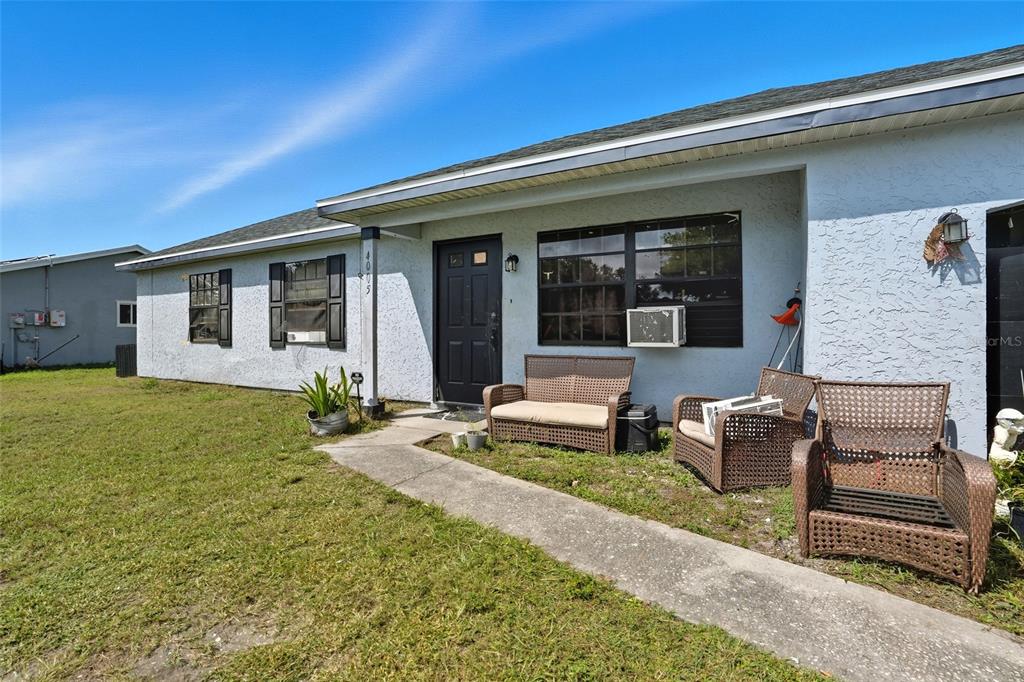 A single-story house with light blue stucco siding, a black front door, and wicker furniture — 4005 W SUNFLOWER CIRCLE, LABELLE, FL