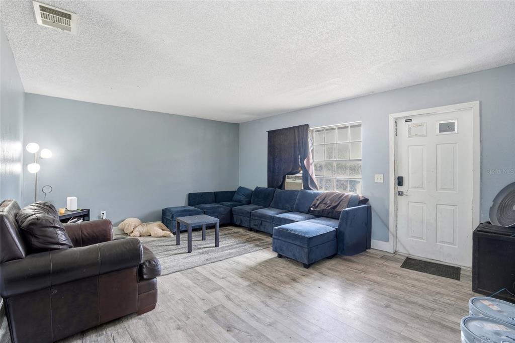A living room features light blue walls, wood-look flooring, a blue sectional, and a leather armchair — 4005 W SUNFLOWER CIRCLE, LABELLE, FL