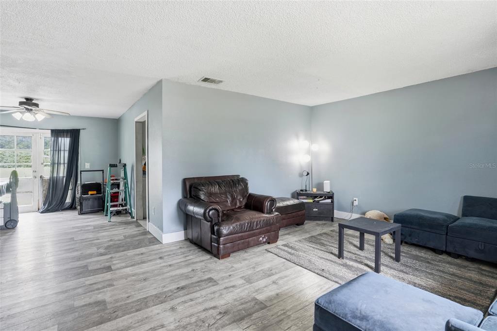 A living room features gray walls, wood-look flooring, a leather armchair, and blue sectional seating — 4005 W SUNFLOWER CIRCLE, LABELLE, FL