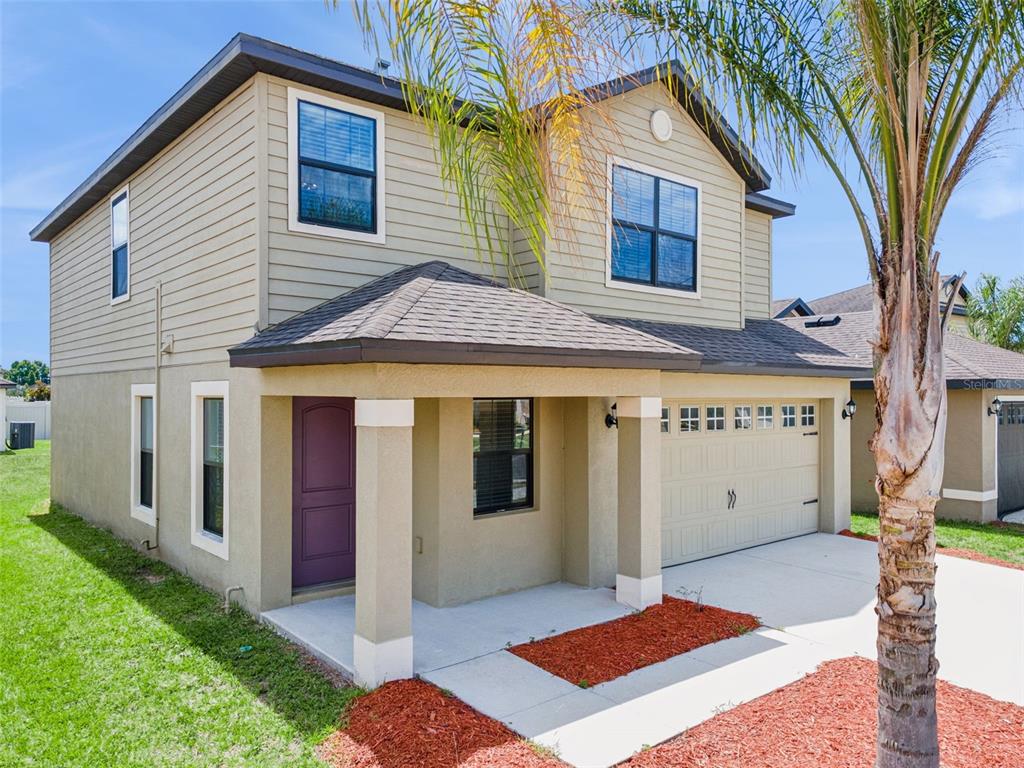 A two-story house with tan siding and stucco, a purple front door, and a garage — 6547 BAIKAL PLACE, LAKELAND, FL