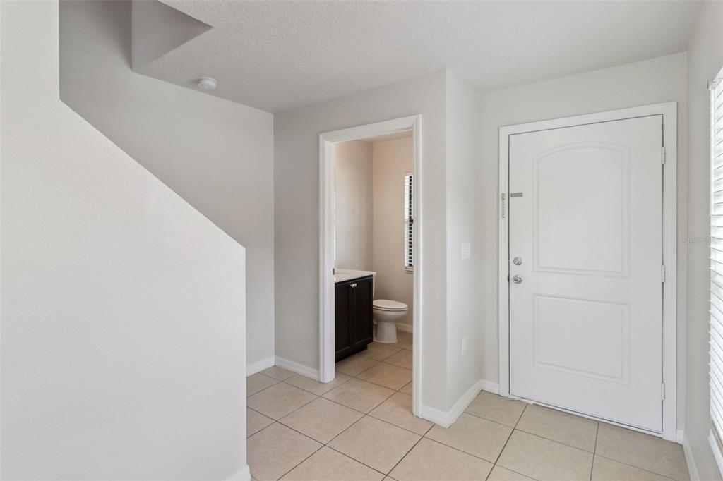 An entryway with tile flooring, a staircase, a white front door, and a half bathroom — 6547 BAIKAL PLACE, LAKELAND, FL