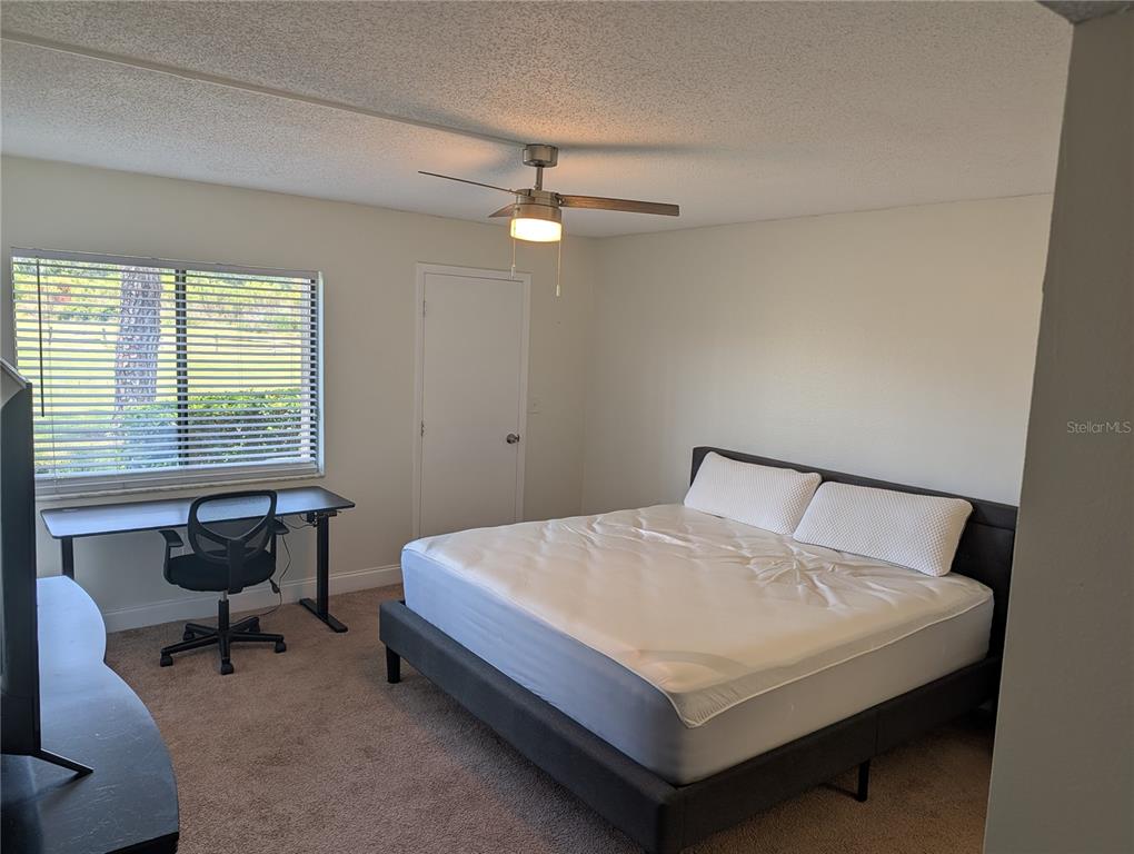 A bedroom features a bed, a desk with a chair, and a ceiling fan — 209 MARY DRIVE UNIT 7, OLDSMAR, FL