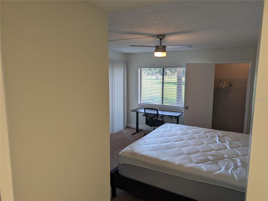 A bedroom features a bed, a desk by the window, and an open closet — 209 MARY DRIVE UNIT 7, OLDSMAR, FL