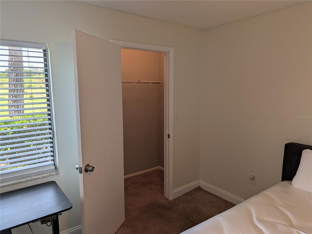 A bedroom features a window with blinds, a closet with an open door, and carpet — 209 MARY DRIVE UNIT 7, OLDSMAR, FL