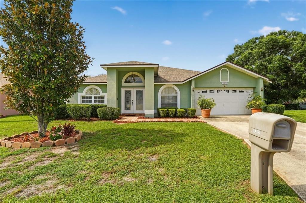 A single-story green house with a two-car garage and a front lawn — 6312 PROMINENCE POINT DRIVE, LAKELAND, FL