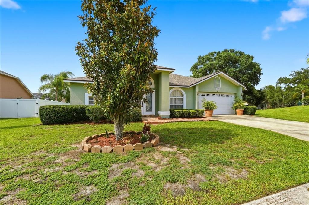 A single-story light green house with a two-car garage and a landscaped front yard — 6312 PROMINENCE POINT DRIVE, LAKELAND, FL