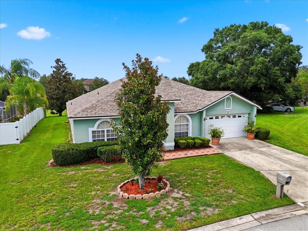 A light green single-story house features a two-car garage, arched windows, and a landscaped yard — 6312 PROMINENCE POINT DRIVE, LAKELAND, FL