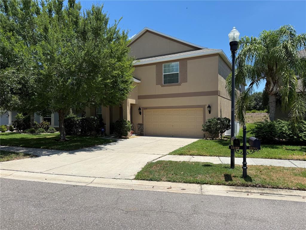 A two-story suburban house with a tan stucco exterior and a two-car garage — 12109 ECHO BASIN COVE, RIVERVIEW, FL