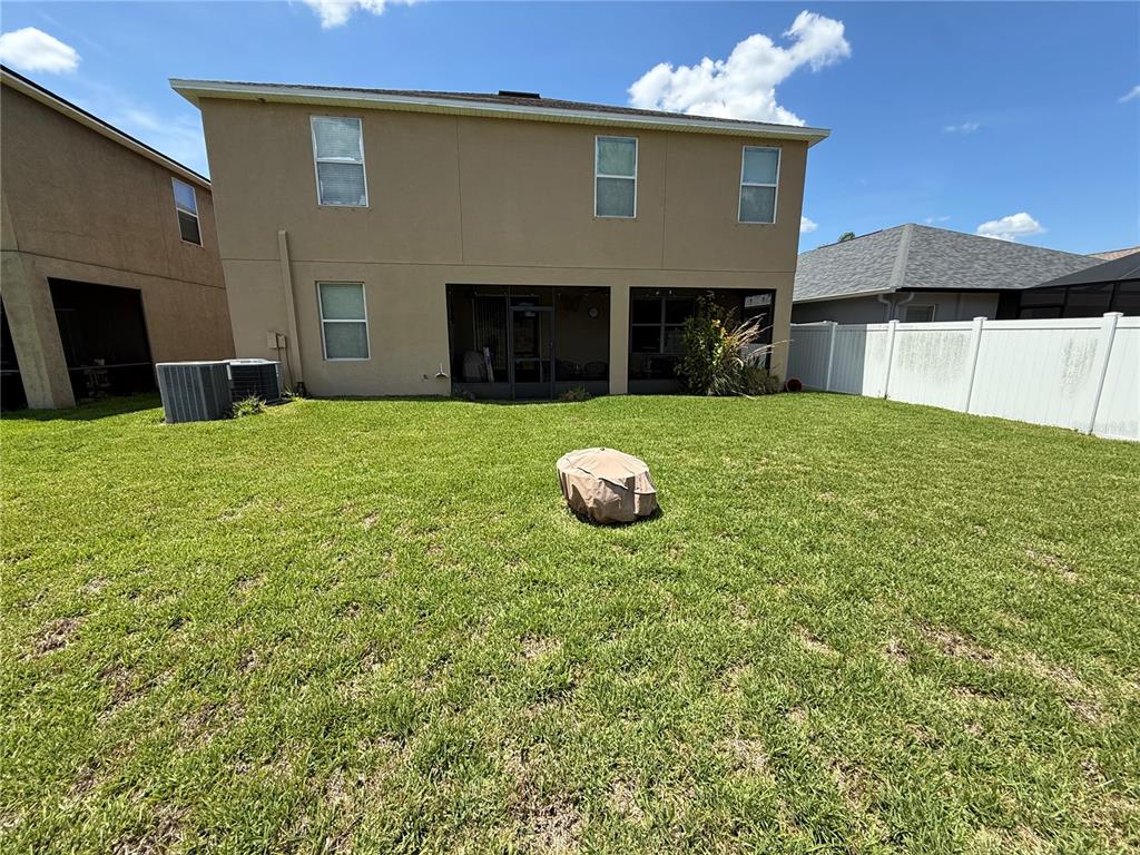 The rear exterior of a two-story tan house features a screened patio and fenced yard — 12109 ECHO BASIN COVE, RIVERVIEW, FL