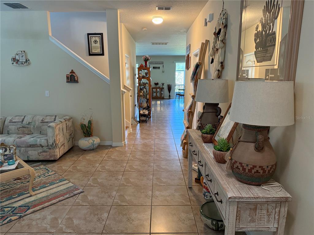 A tiled hallway leads from a living area past a console table toward a dining space — 12109 ECHO BASIN COVE, RIVERVIEW, FL